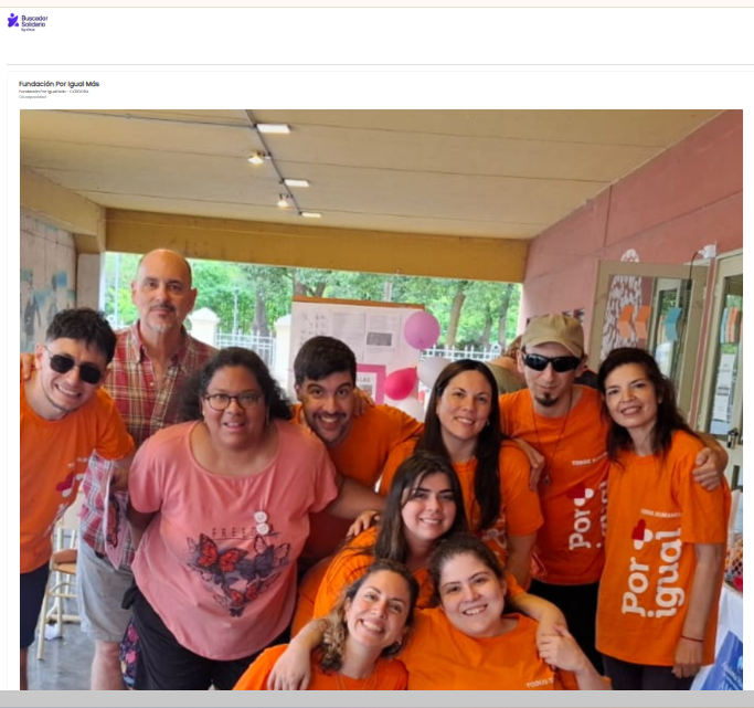 grupo de nueve personas, todas sonriendo y posando juntas de forma cercana y amistosa. La mayoría de ellas lleva camisetas de color naranja brillante con el logo de la Fundación Por Igual Más, que dice 'Por Igual Más'. El grupo incluye hombres y mujeres, algunos con distintas discapacidades, abrazándose o con los brazos sobre los hombros de los demás. Arriba, pequeño, se ve el logo Buscador Xinus en letras azules.